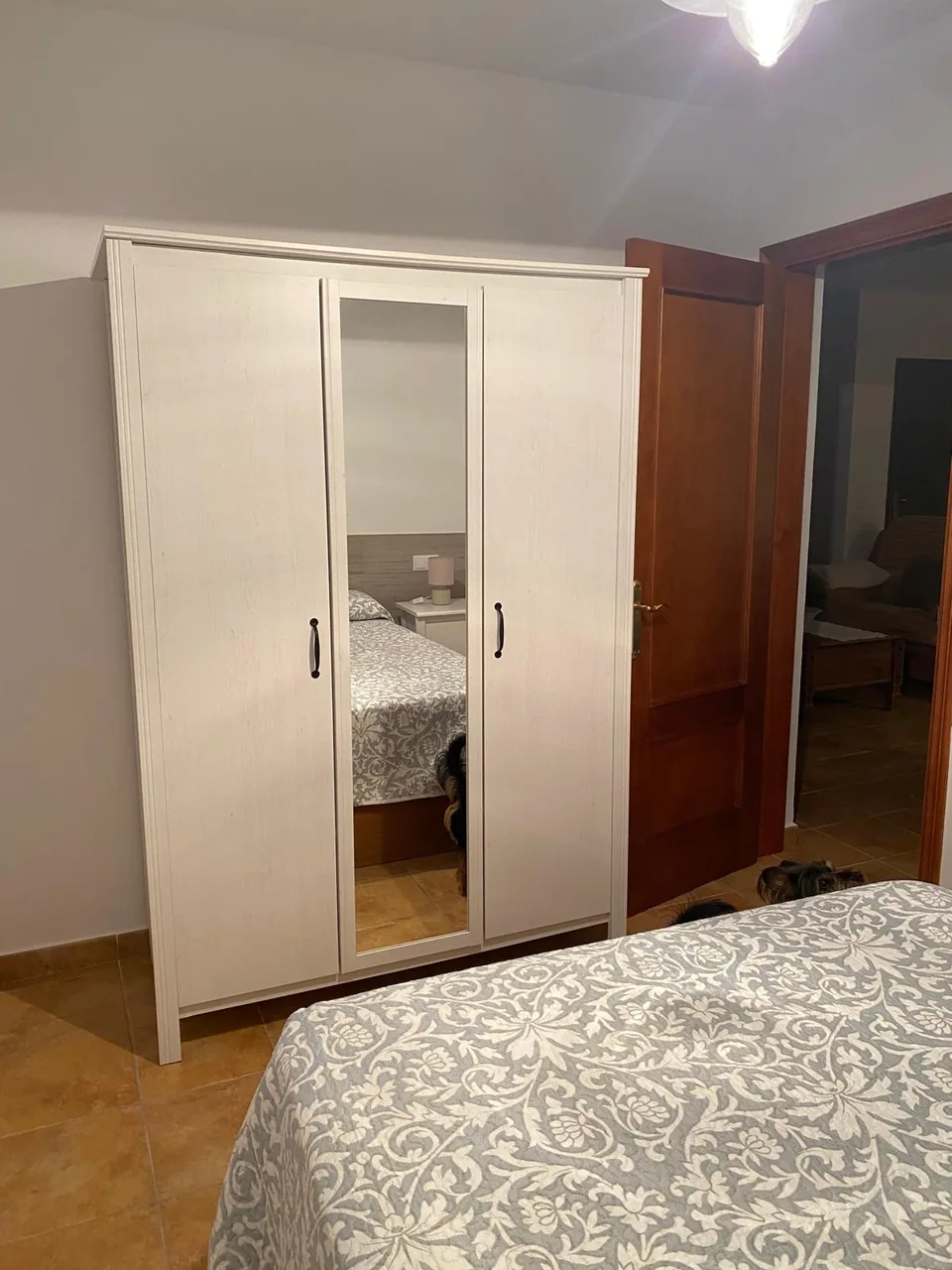 Armario blanco con espejo en el dormitorio de cabecero claro