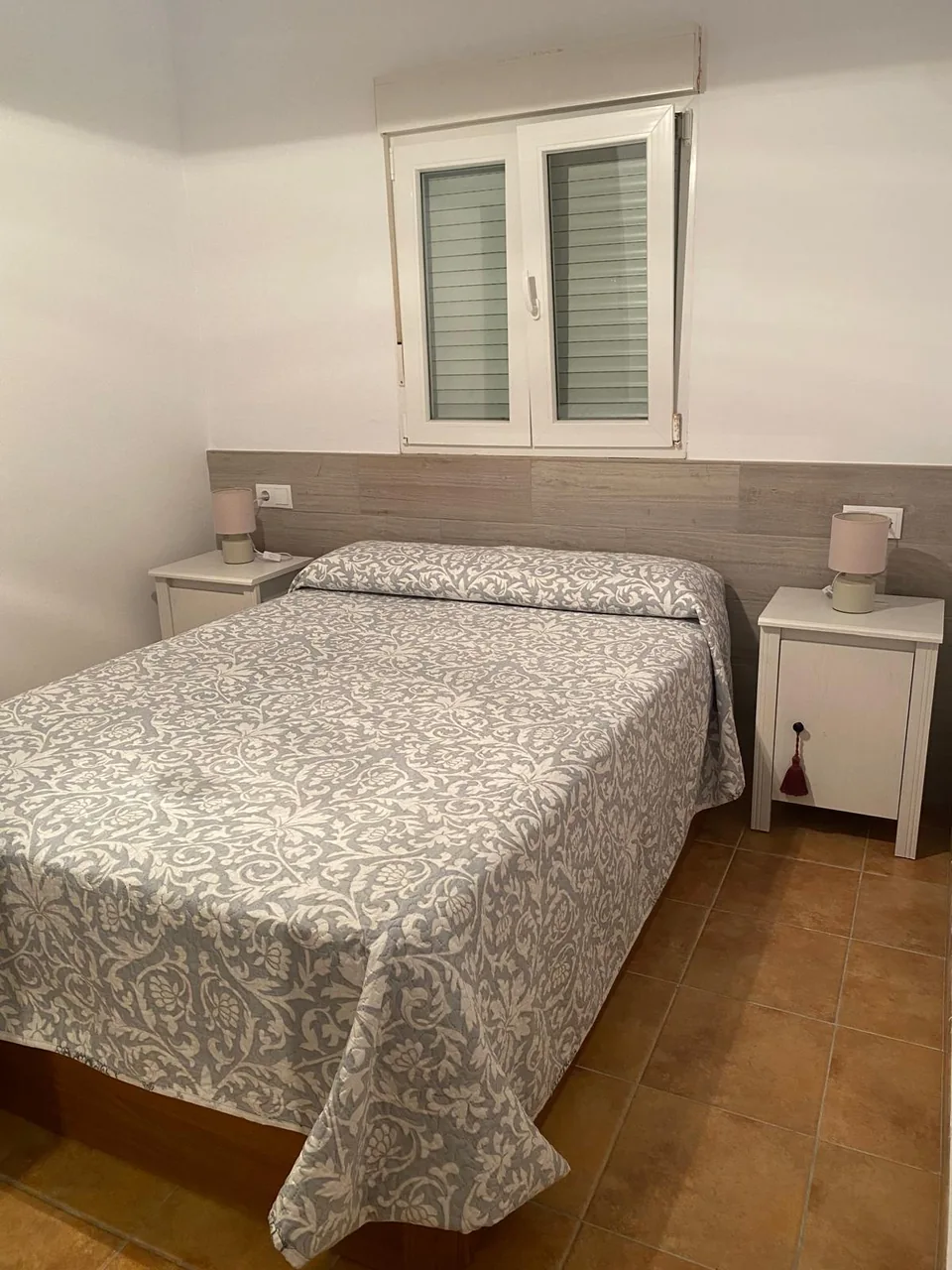 Dormitorio con cama de matrimonio, cabecero claro y mesillas blancas