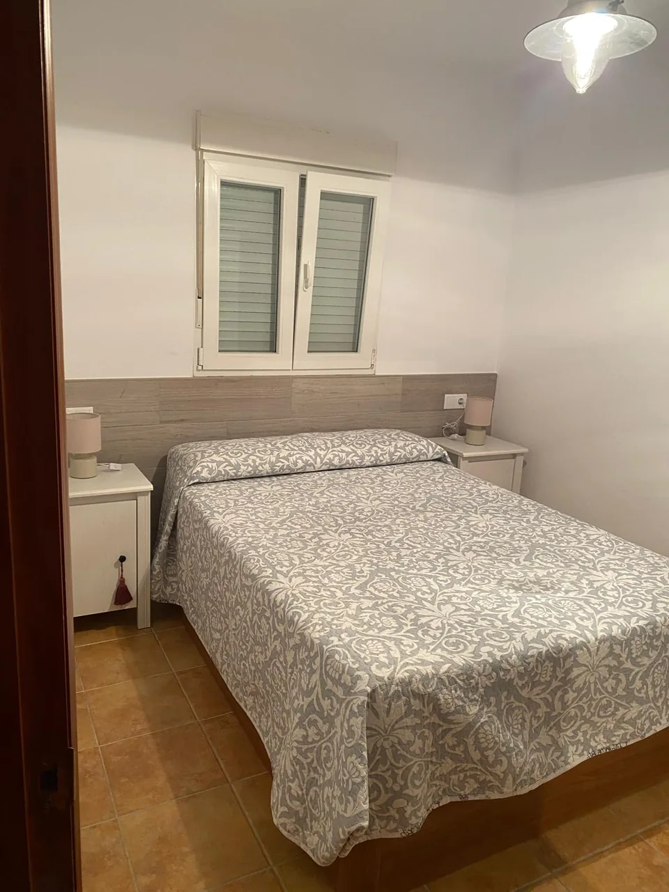 Vista desde la entrada del dormitorio con cabecero claro y cama de matrimonio