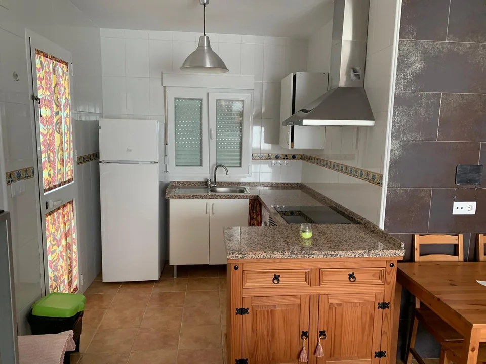 Encimera de cocina, campana extractora y frigorífico junto a la ventana