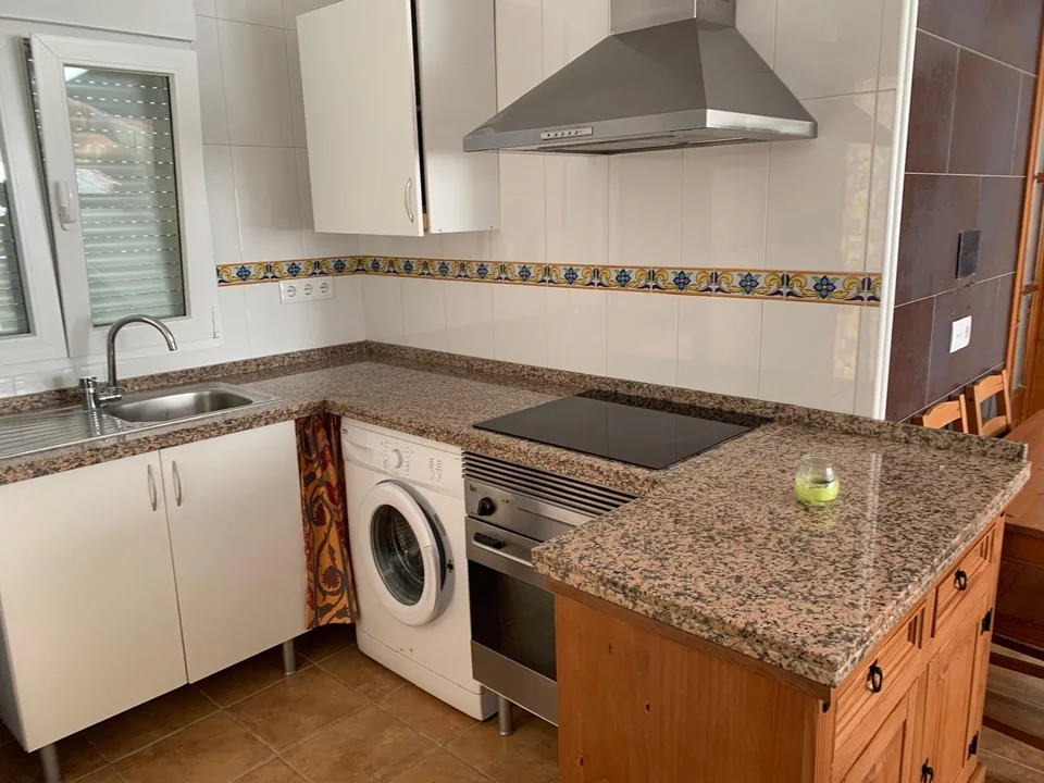 Fregadero bajo la ventana, placa de cocina y lavadora de Casa Poniente