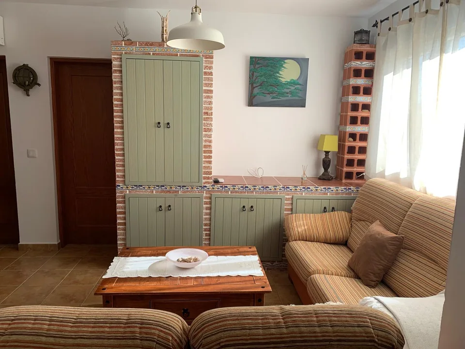 Mueble de obra verde y sofá en el salón de Casa Poniente
