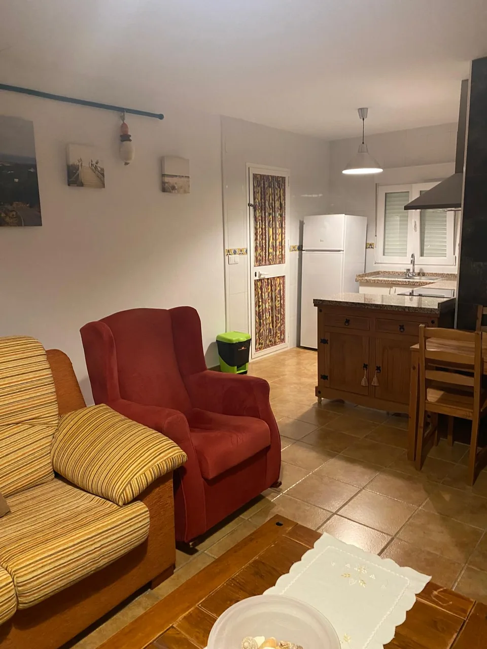 Salón con sillón rojo y vista hacia la cocina abierta