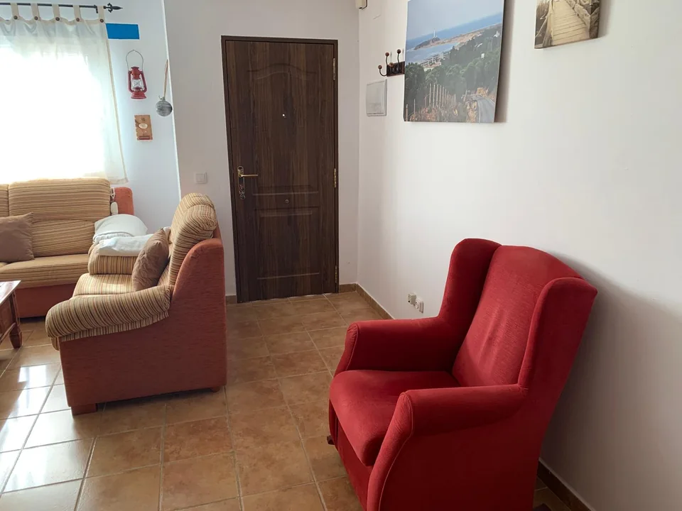 Sillón rojo y zona de estar junto a la ventana del salón