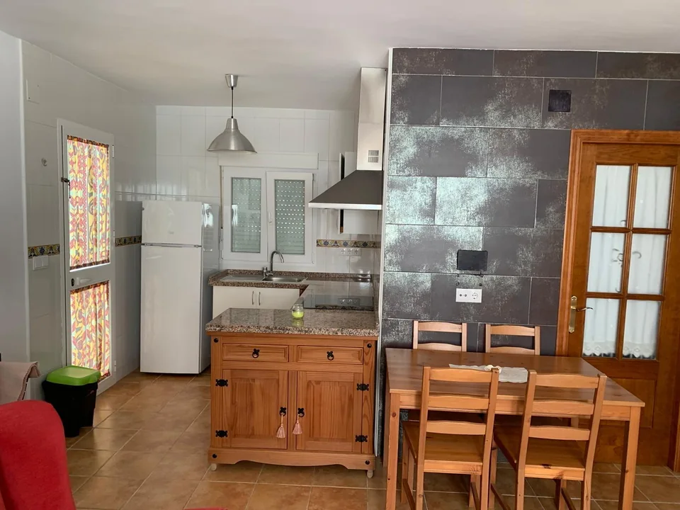 Vista general de la cocina con frigorífico, encimera y barra de madera